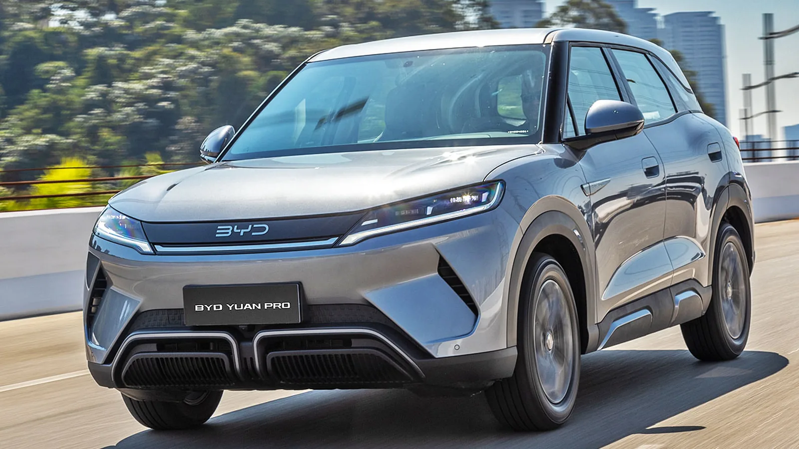 BYD Yuan Pro azul elétrico trafegando em avenida movimentada, vista lateral que realça suas linhas.