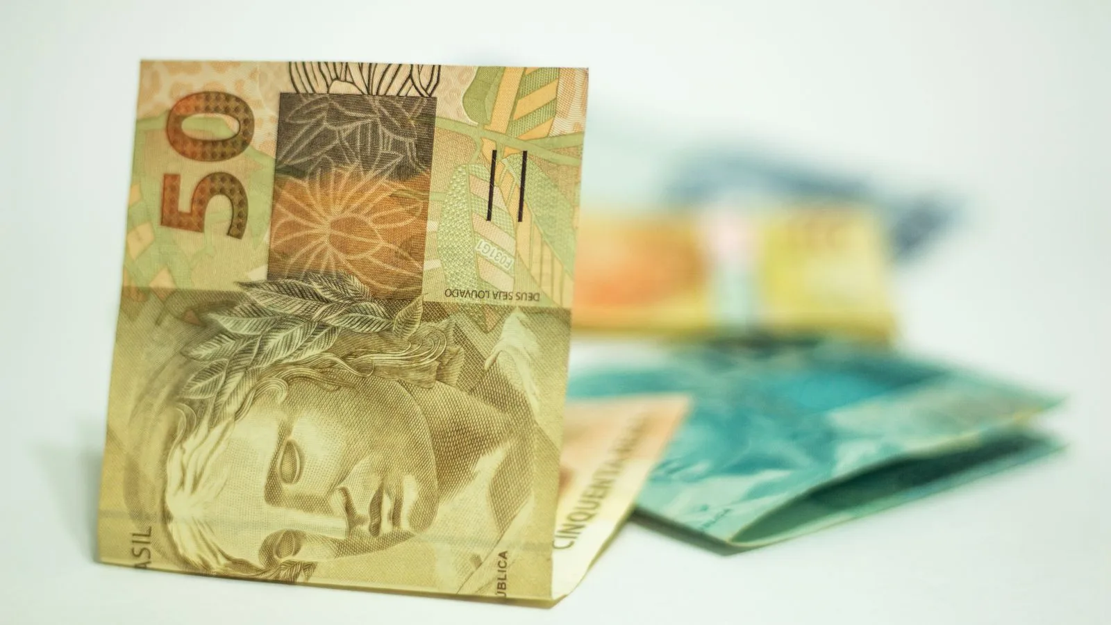 Brazilian Real banknotes in focus with 50 denomination displayed prominently.