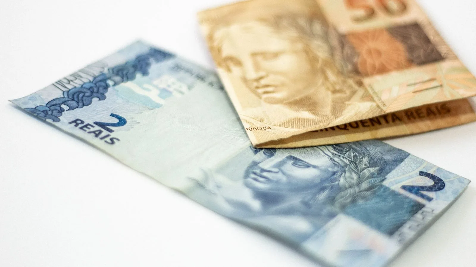 Close-up view of Brazilian banknotes, 2 and 50 reals, on a white background.