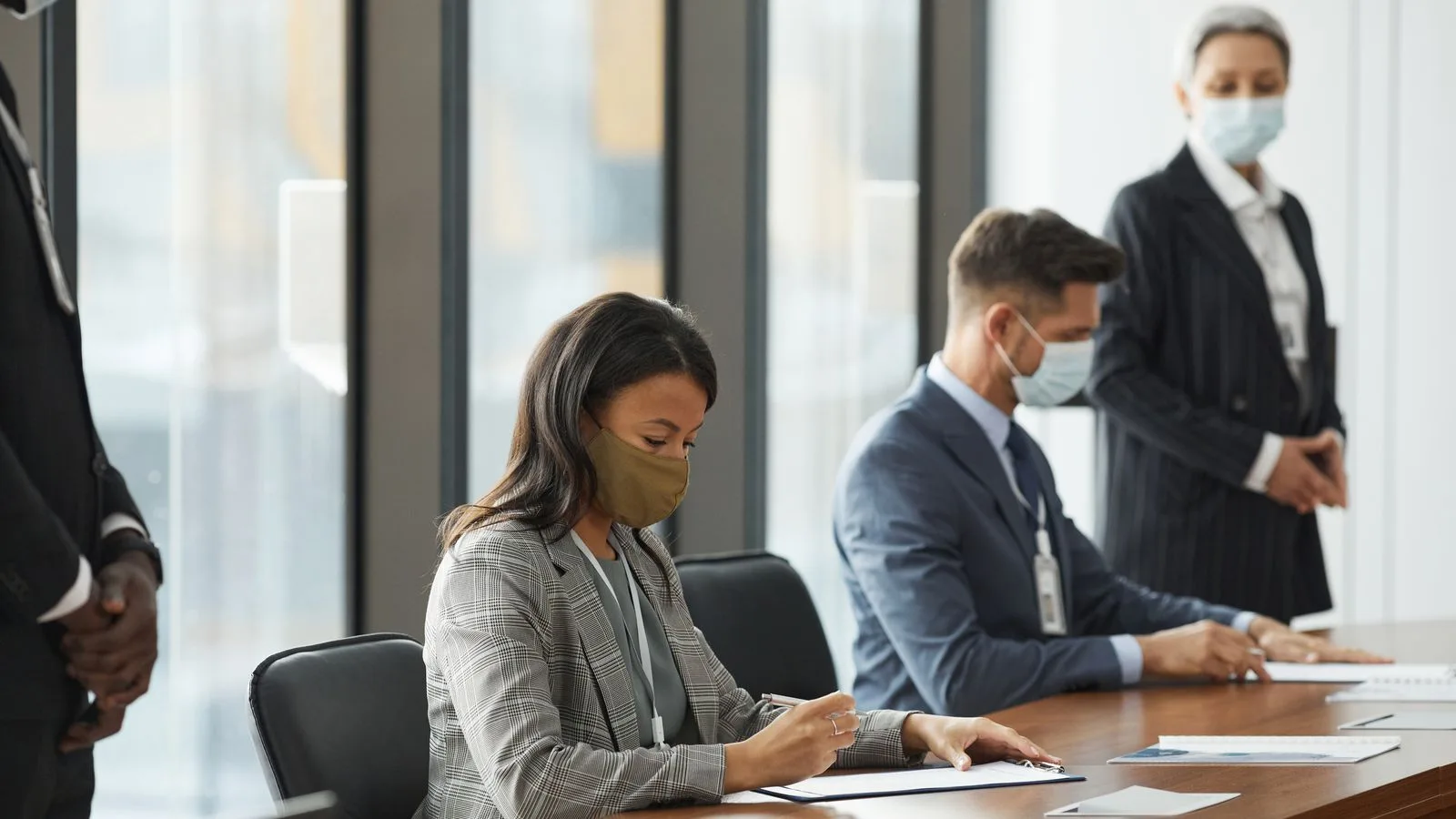 Professionals in face masks having a business meeting in a modern conference room.