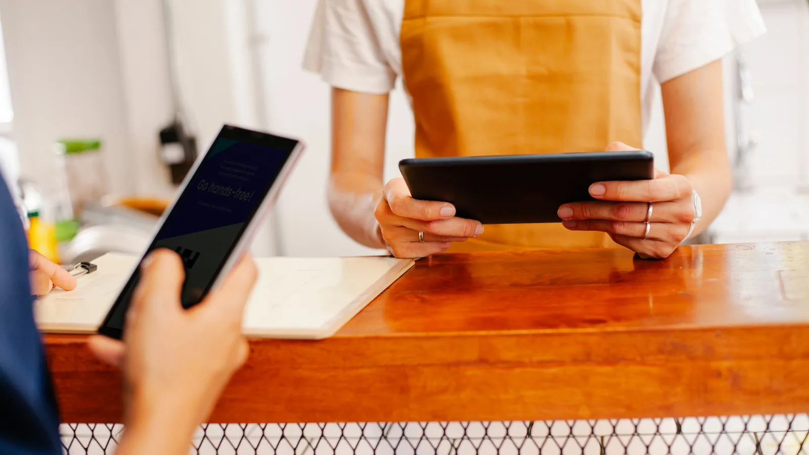 Crop anonymous female colleagues surfing internet on cellphone with black screen and tablet in cafe