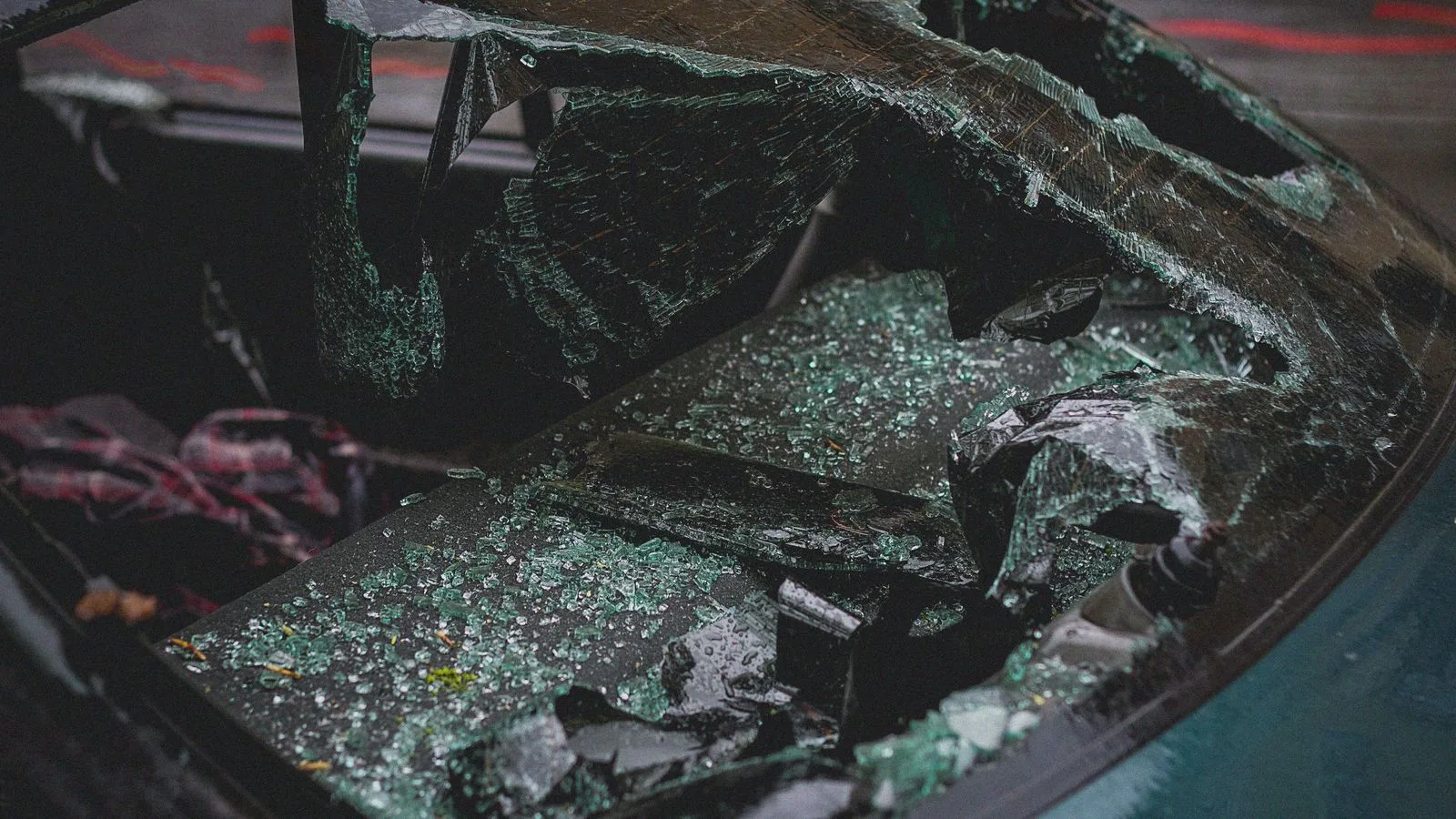 Detailed view of shattered car windshield after accident, emphasizing damage and broken glass.