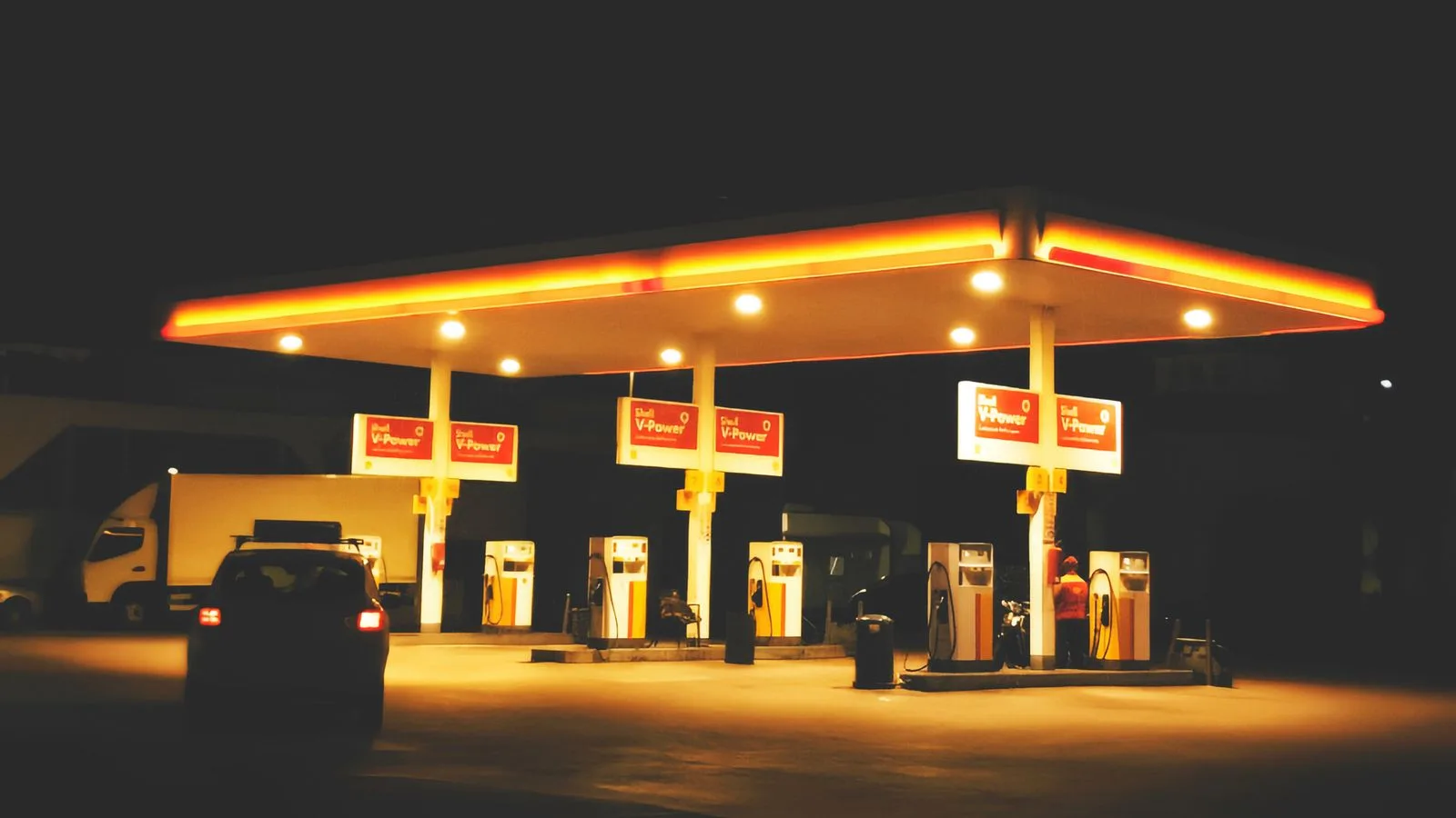 A gas station lit up at night, showcasing signage and fueling pumps under bright lights.
