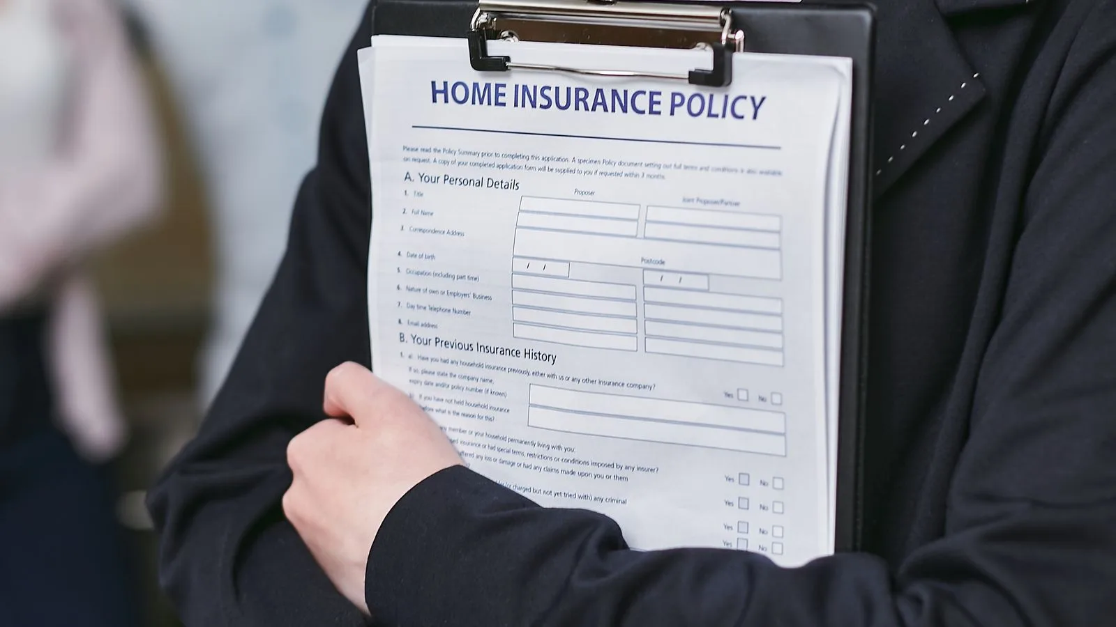 Close-up of a person holding a home insurance policy on a clipboard, captured indoors.