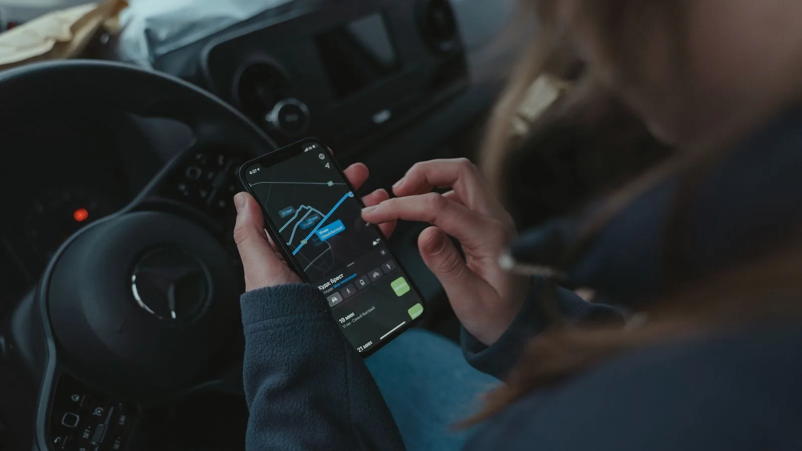 Person using GPS navigation app on smartphone inside car for directions.