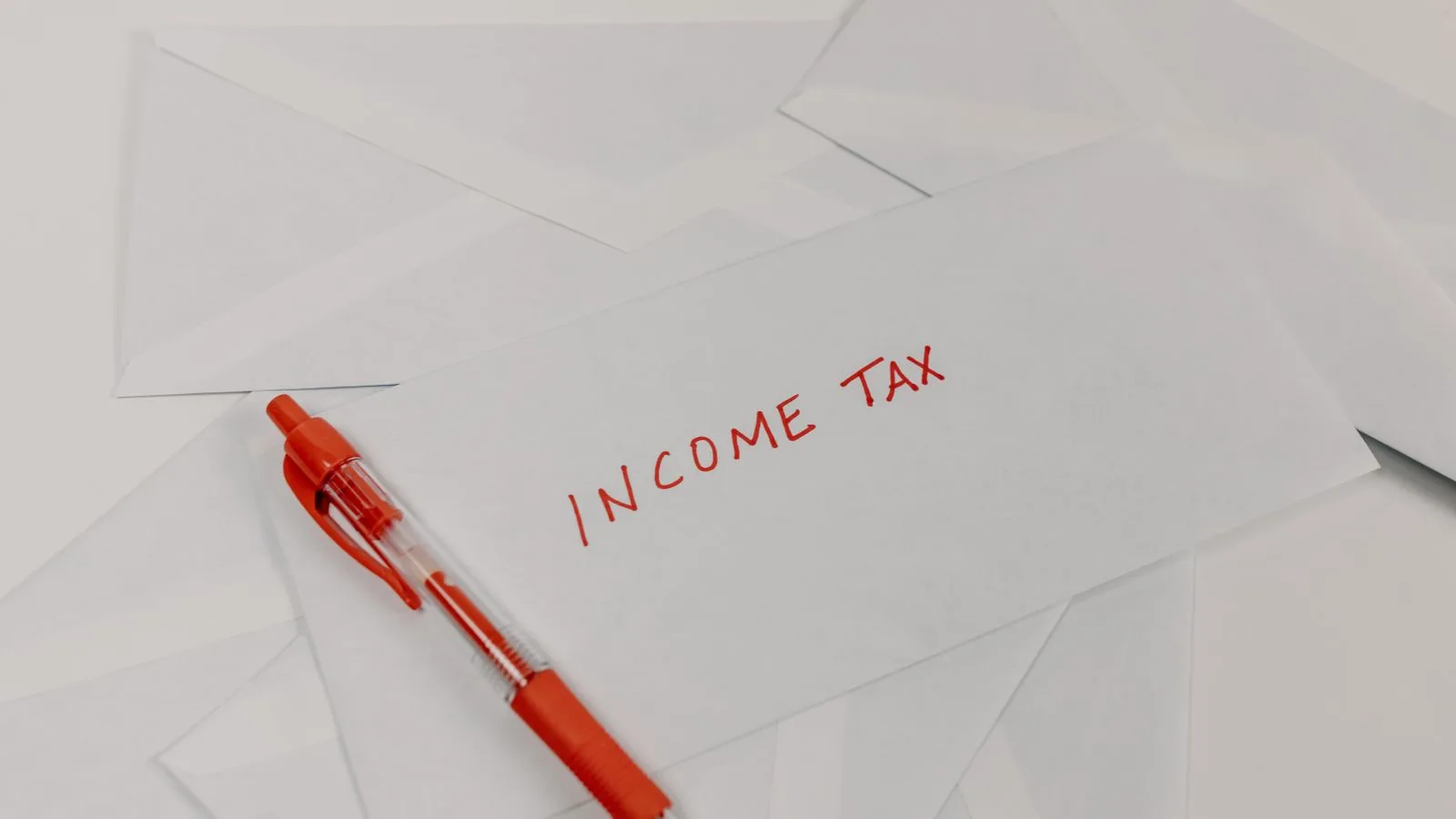 Studio shot of income tax envelope with red pen for accounting and tax season preparation.