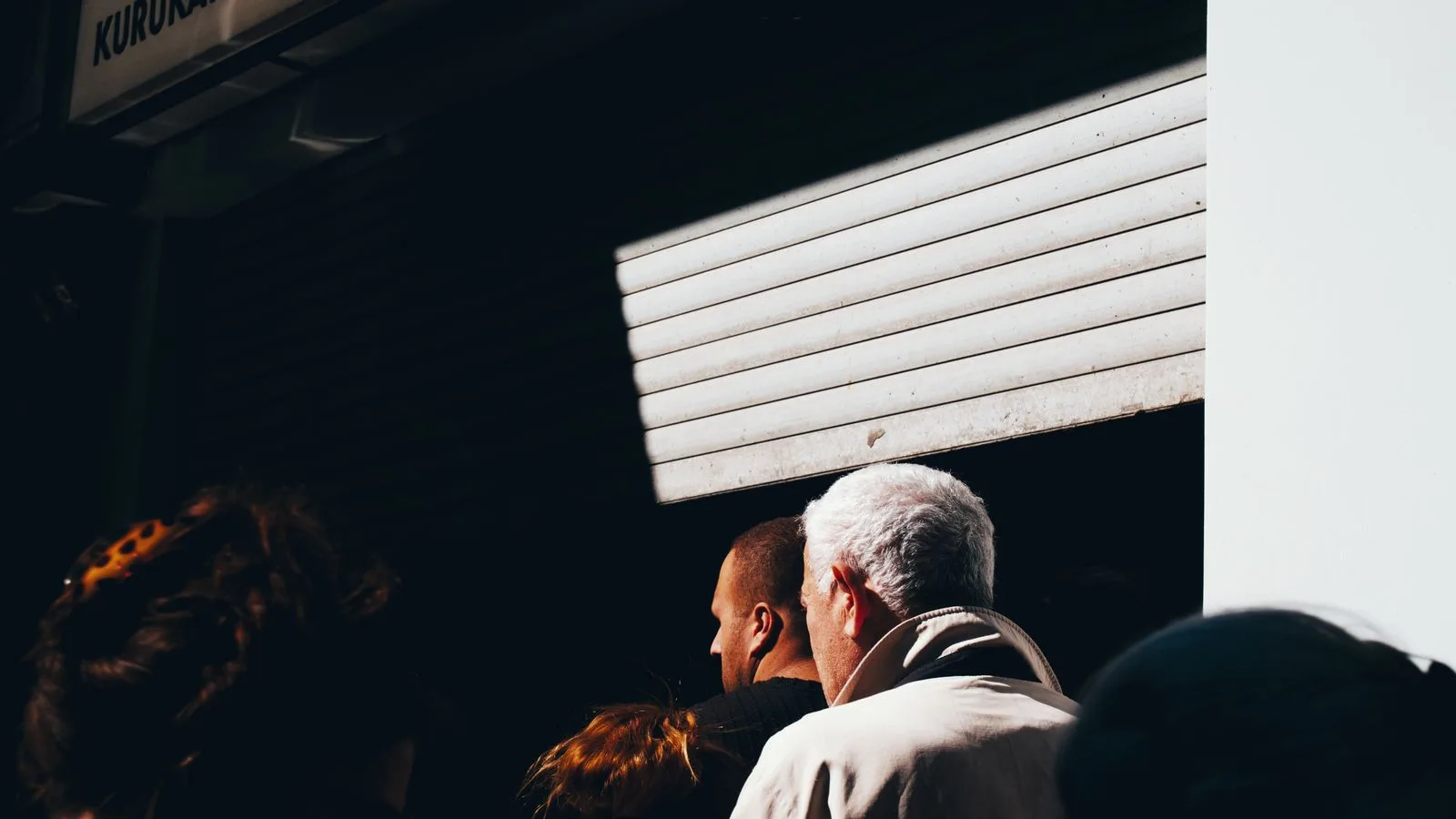A group of people stand in line outside Kurukahveci Mehmet Efendi under dramatic lighting.