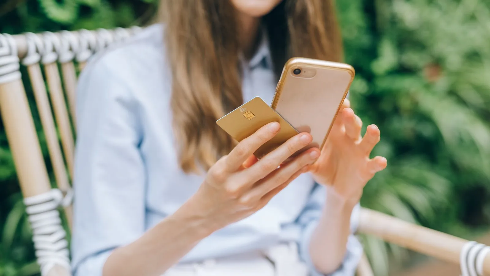 A woman making an online purchase using a smartphone and credit card outdoors.