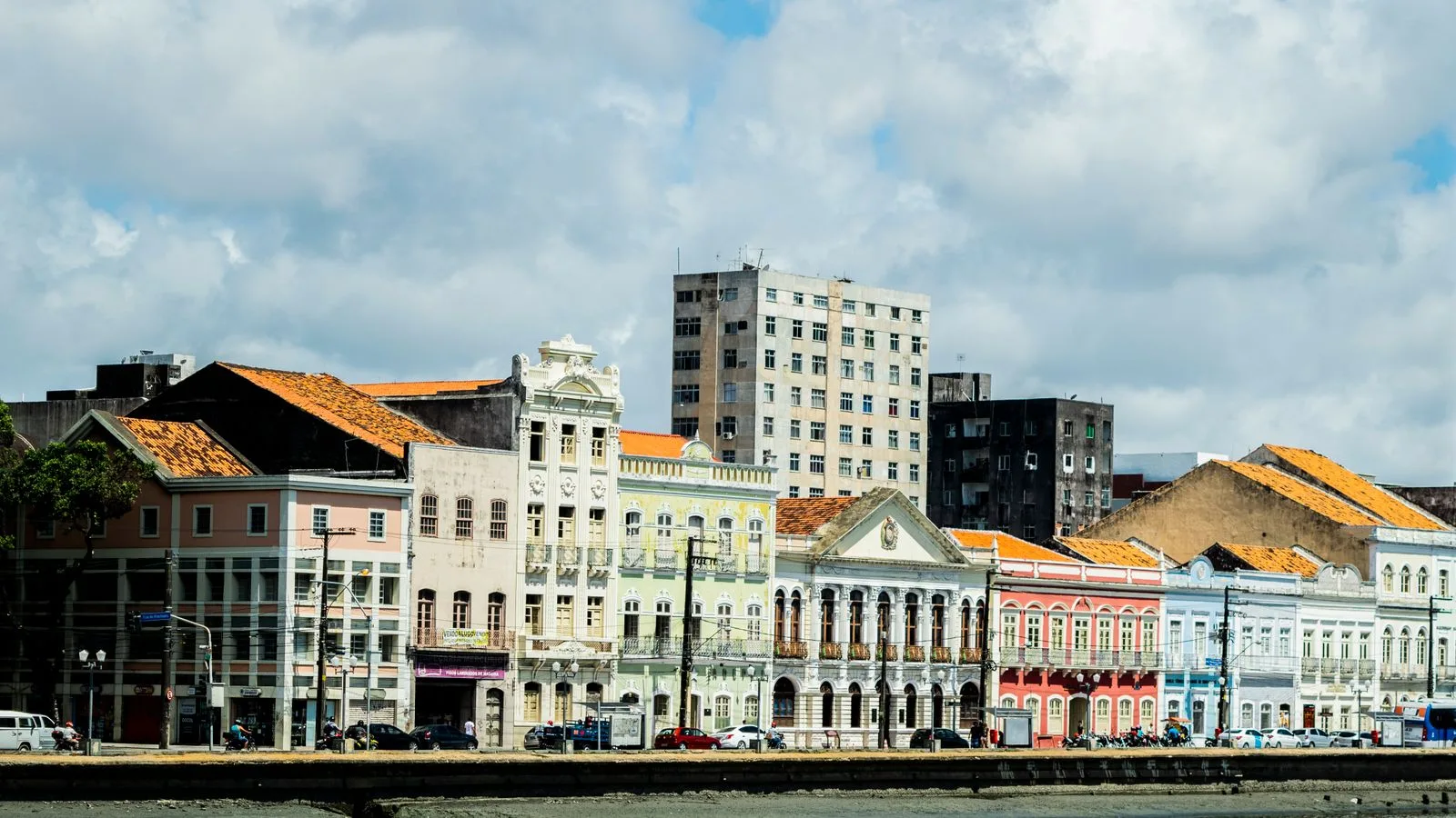 Colorful colonial buildings along Recife's riverfront showcase vibrant Brazilian architecture under bright skies.