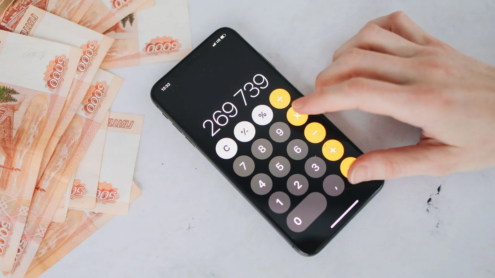 Person using smartphone calculator with Russian rubles on a table, representing financial planning.