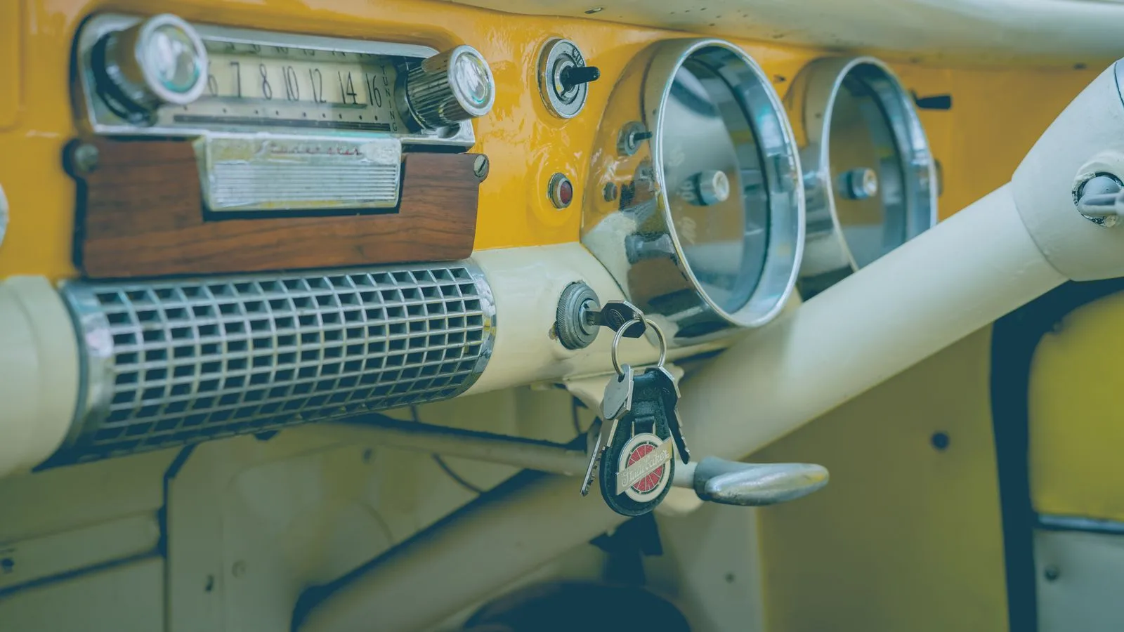 Close-up of a classic vintage car dashboard featuring an analog radio, speedometer, and keys.