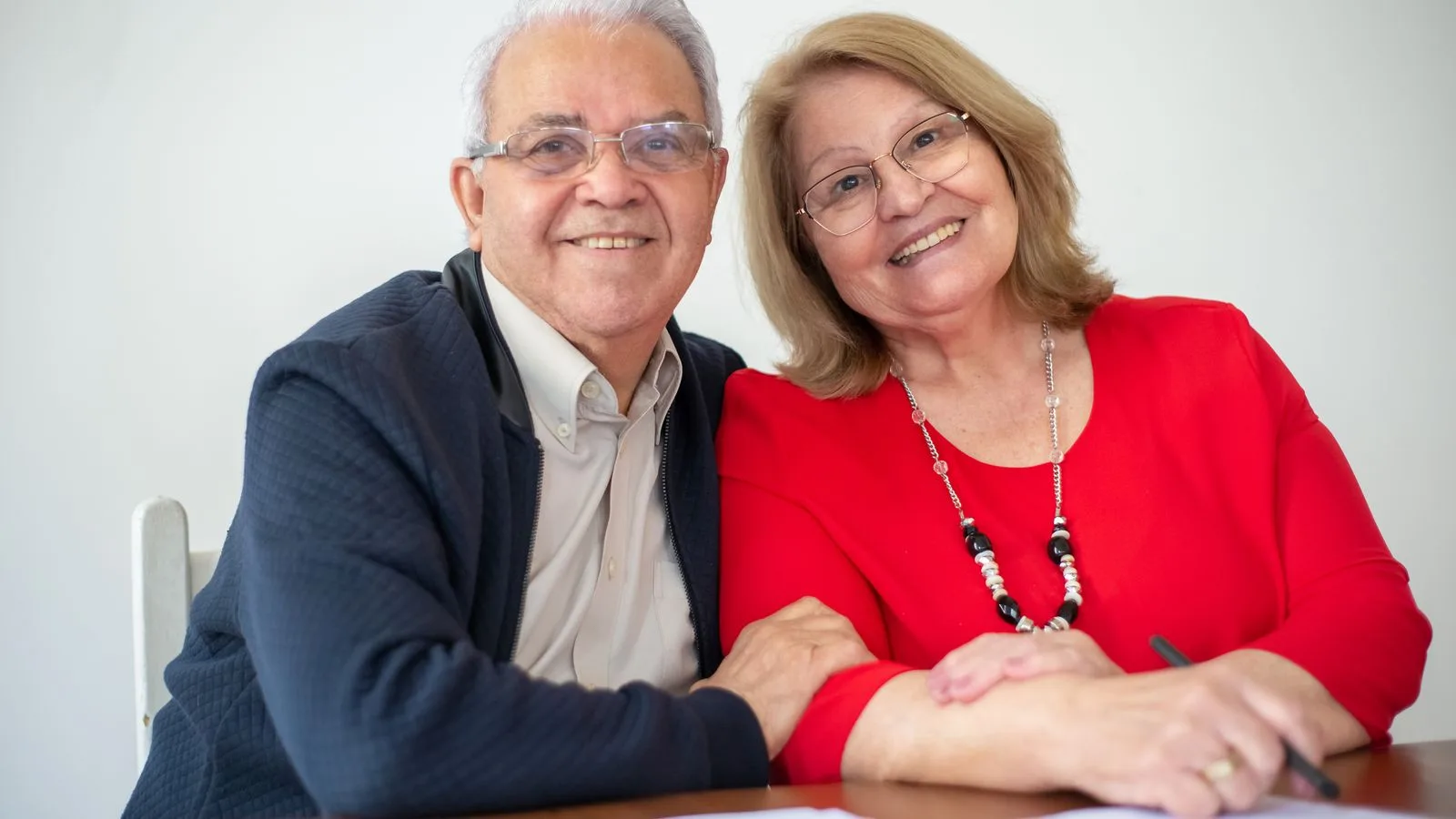 Elderly couple embracing and signing papers, sharing a warm and happy moment together.