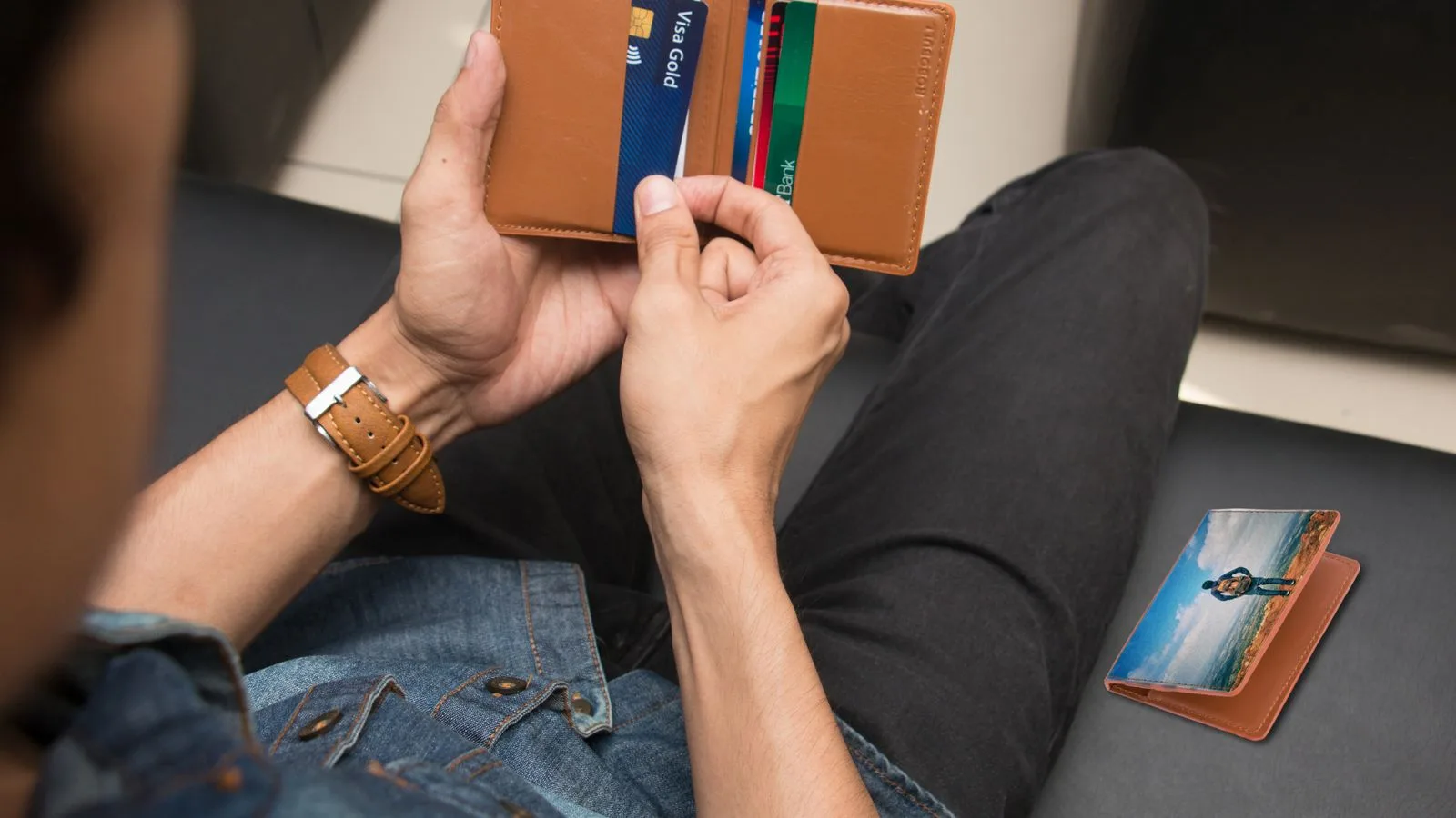 A close-up of a man holding a wallet containing credit cards and an ID inside a room.