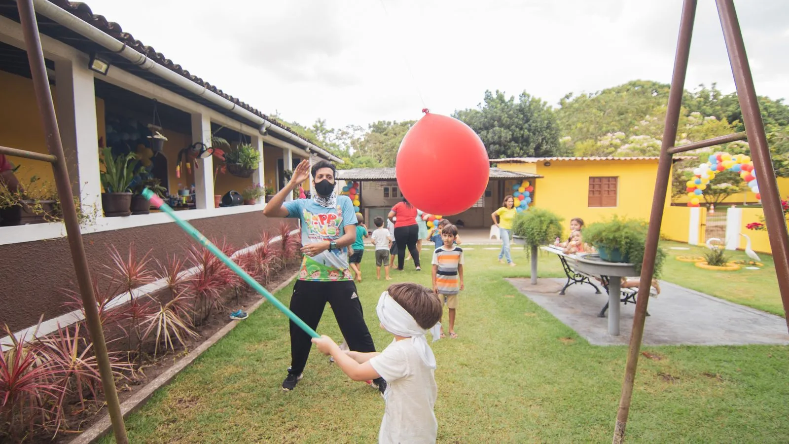 Kids playing a fun balloon game in a vibrant outdoor birthday party setting.