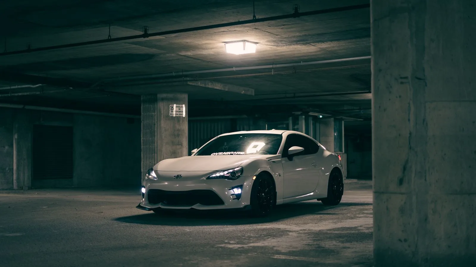 A modern white sports car parked in a dim garage, exuding a mysterious ambiance.