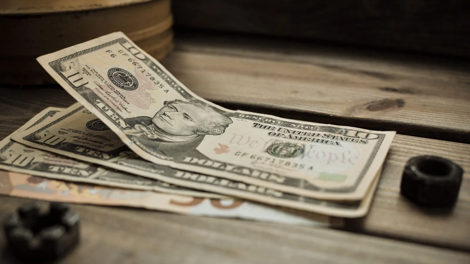 A stack of US dollar bills on a rustic wooden table close-up view.