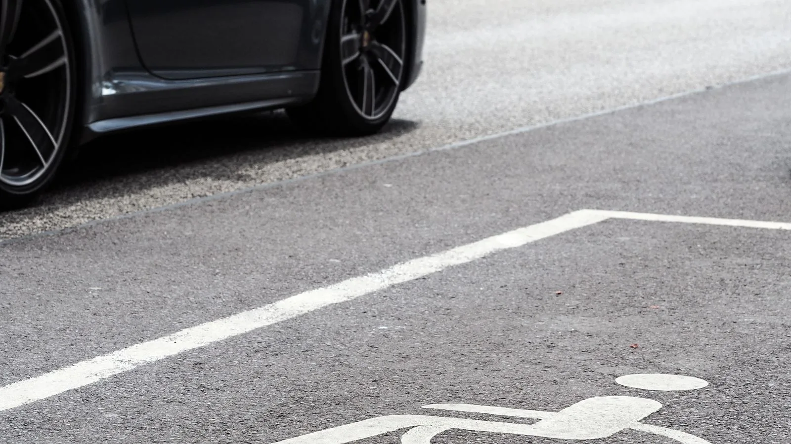 A luxury vehicle parked in a designated disabled parking space on an urban street.