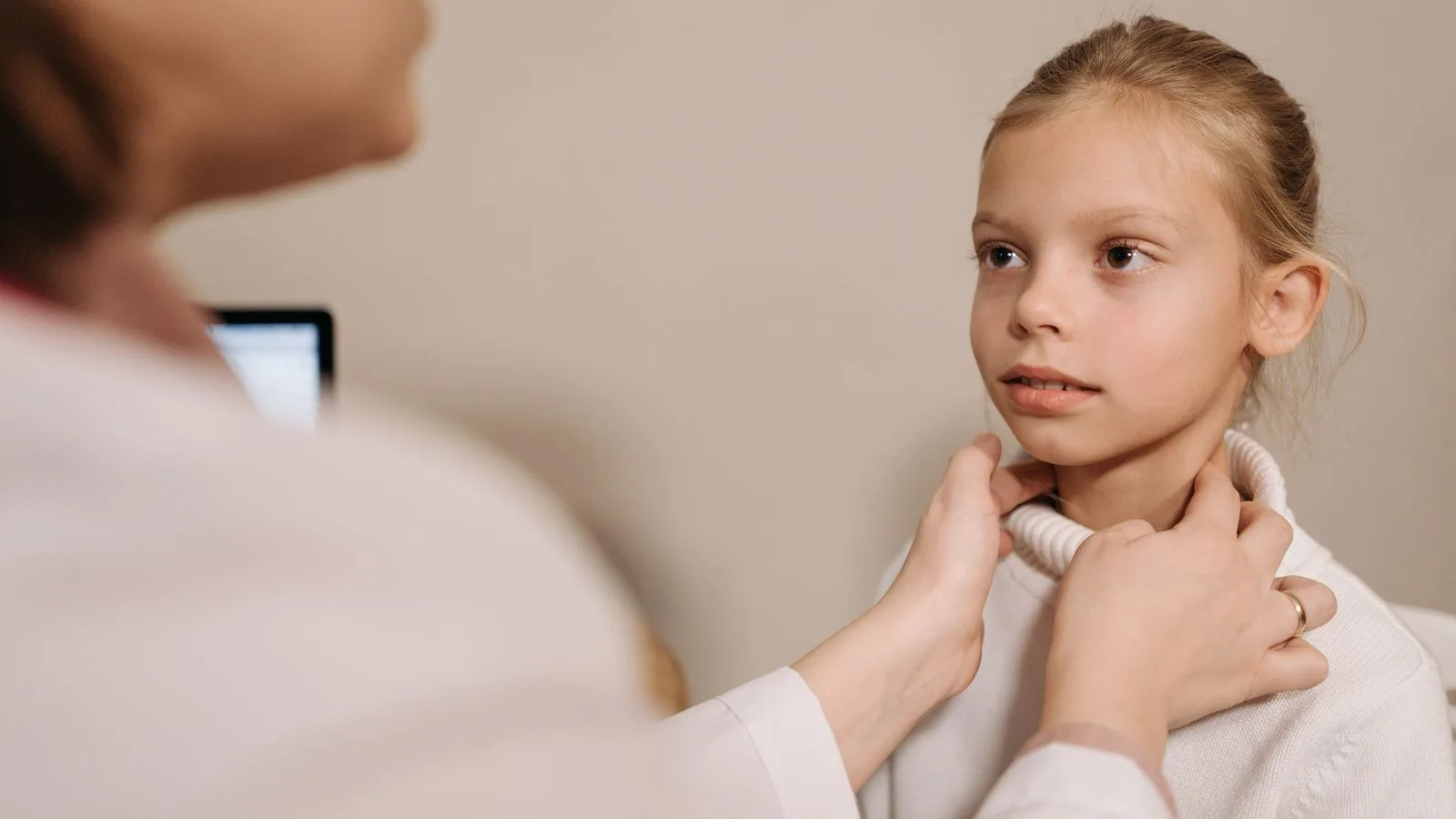 A doctor performing a medical check on a child during an appointment in a clinic.