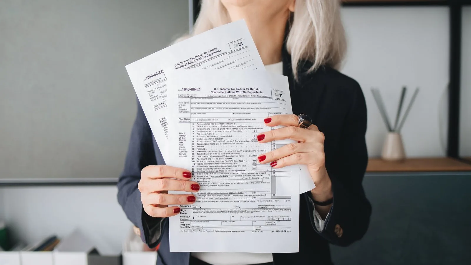 Businesswoman holding tax documents, ready for filing or review, in a professional office setting.