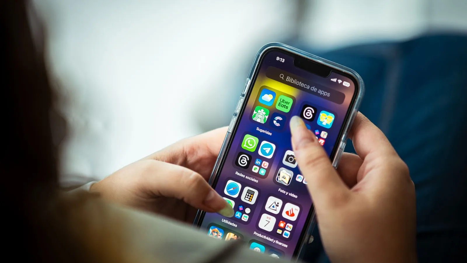 Close-up of a woman holding a smartphone displaying various apps.