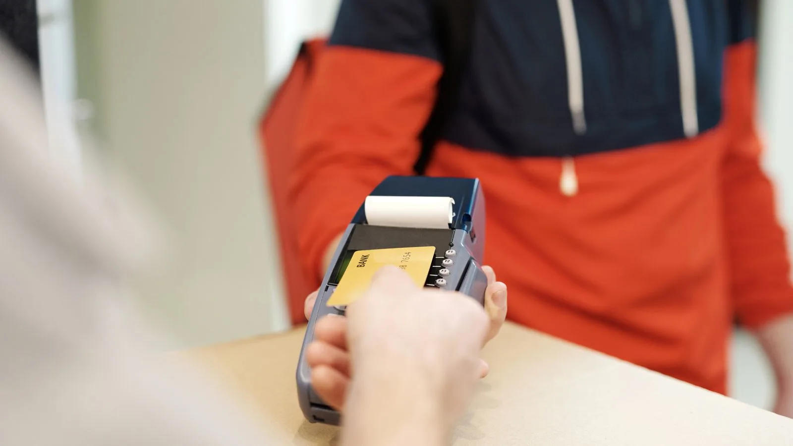 Close-up view of a contactless payment transaction using a credit card on a terminal device.