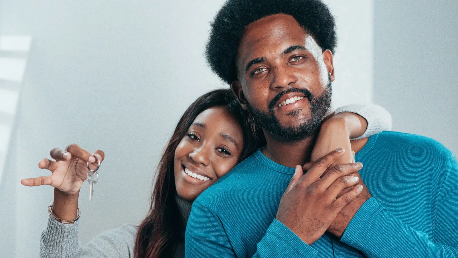 Joyful couple proudly holding keys to their new home, symbolizing fresh beginnings.