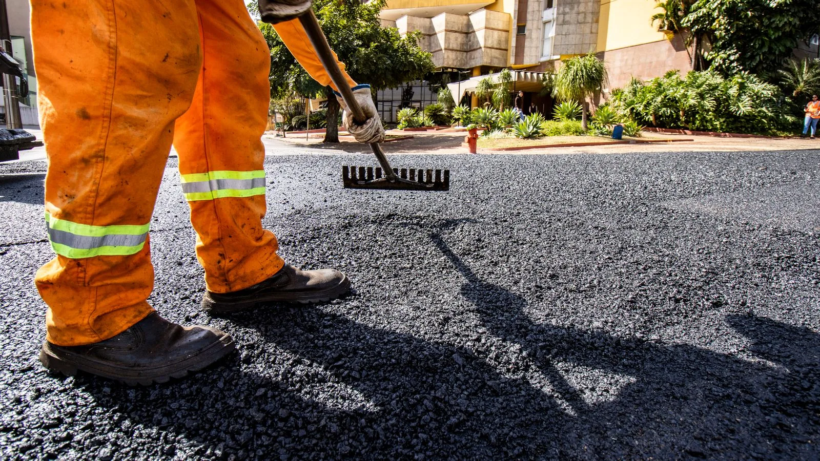 Worker in orange gear paving a road in Londrina city during daytime.