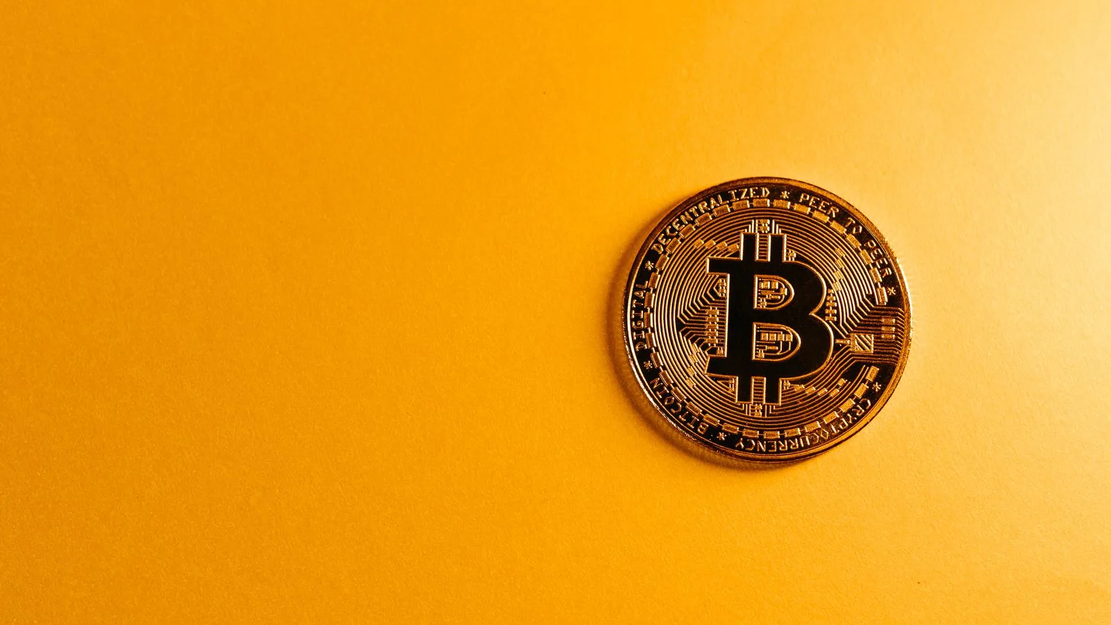 Close-up of a Bitcoin cryptocurrency coin on a vibrant yellow background, symbolizing digital money.
