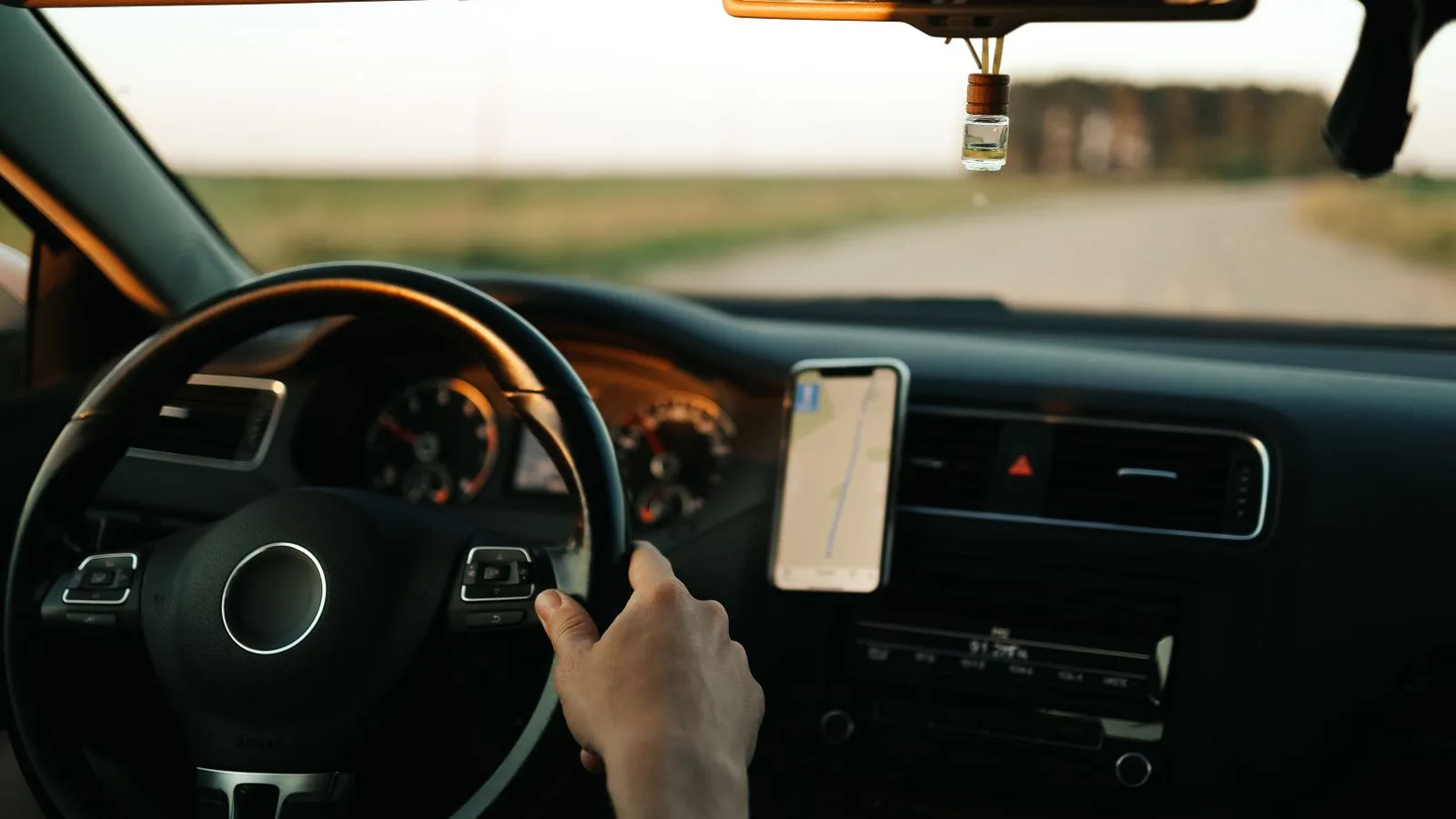 Interior of a car with GPS navigation, focusing on the driver and dashboard during the day.