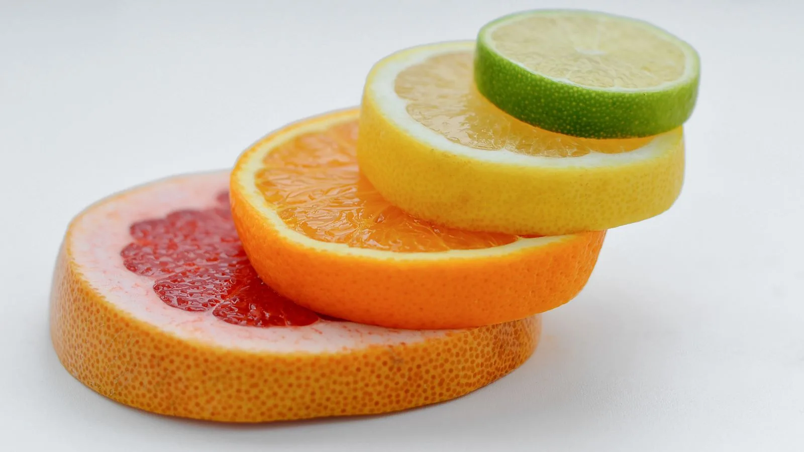 Colorful stack of citrus slices - grapefruit, orange, lemon, lime - showcasing freshness and health benefits.