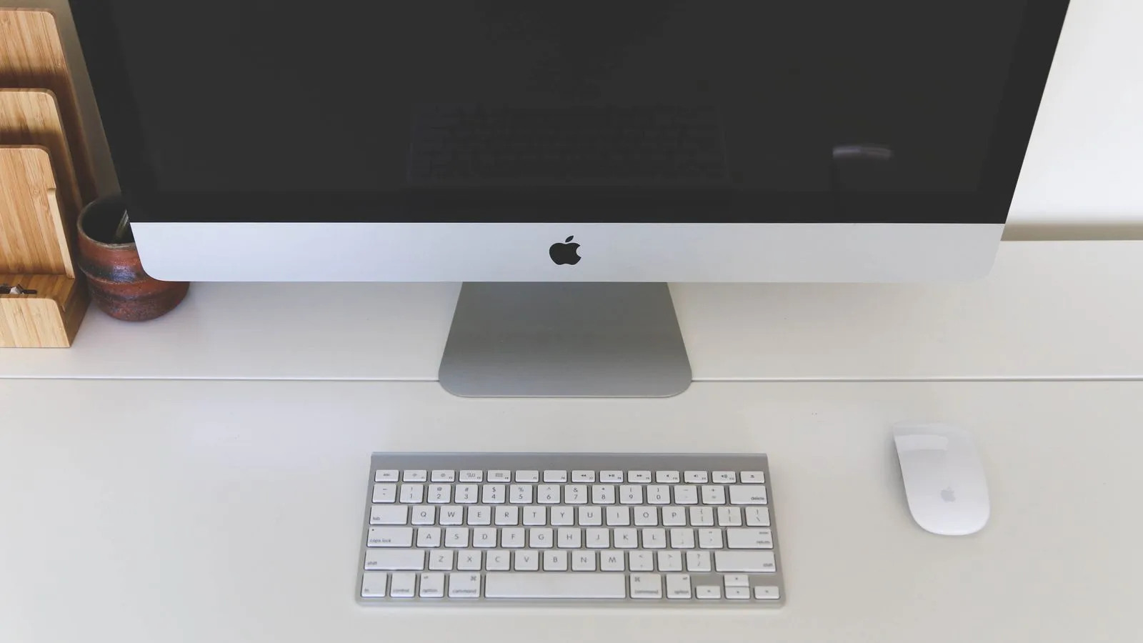 Minimalist home office workspace featuring a desktop computer, keyboard, and mouse on a white desk.