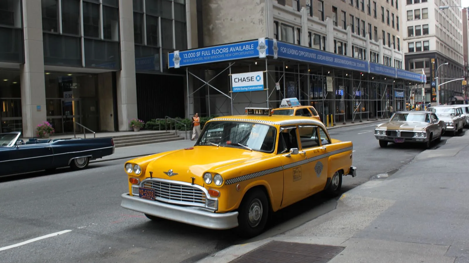 Vintage yellow taxi cab parked on a bustling New York City street.