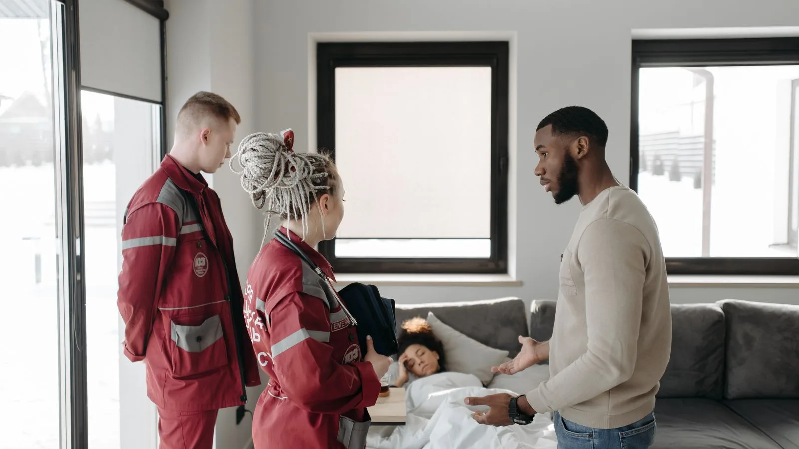 Paramedics assisting a patient at home, illustrating urgency and healthcare support indoors.