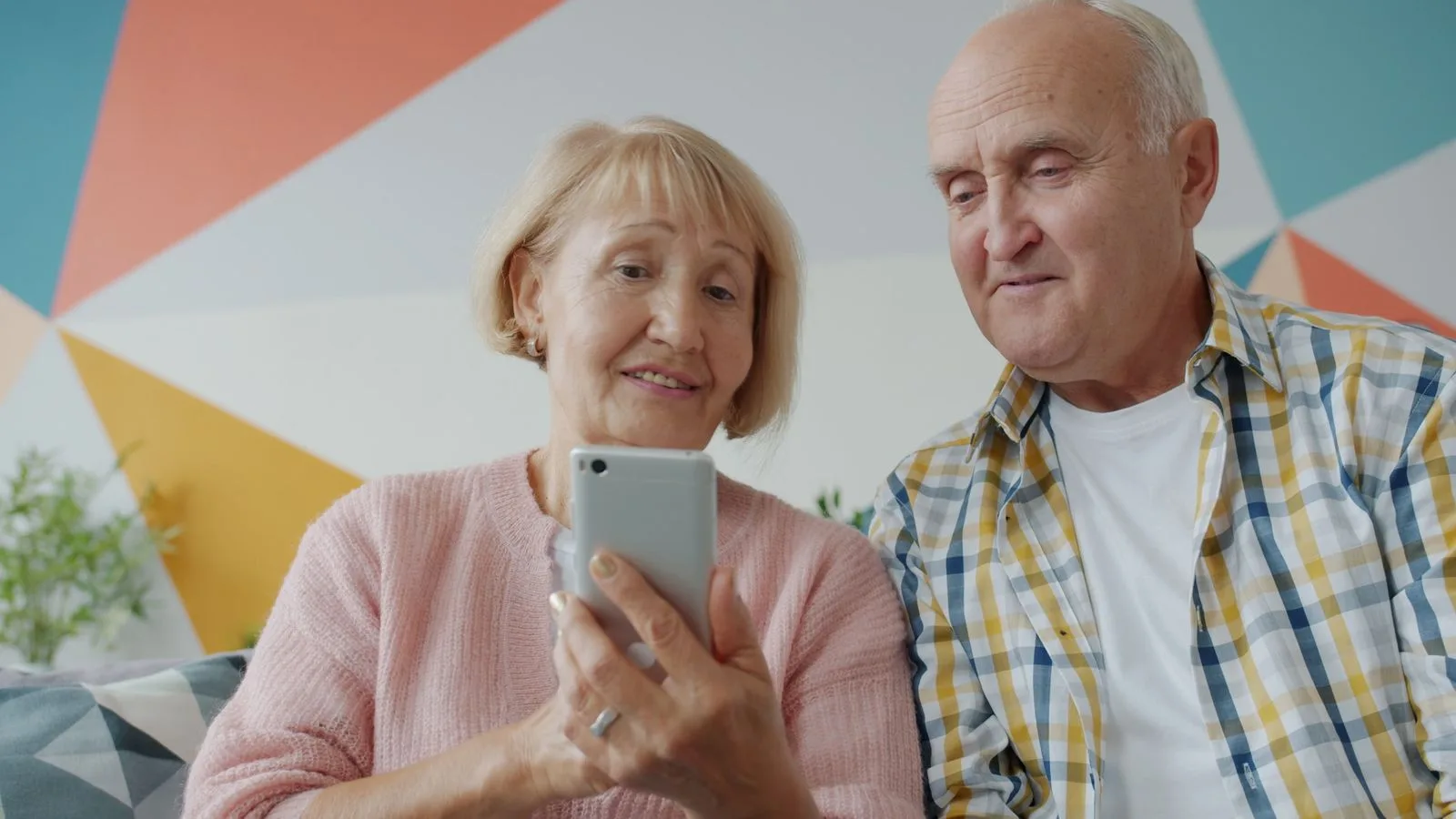 Senior couple enjoying smartphone in a modern living room.
