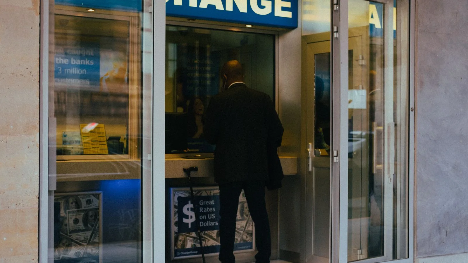 A businessman changes money at a currency exchange counter indoors.