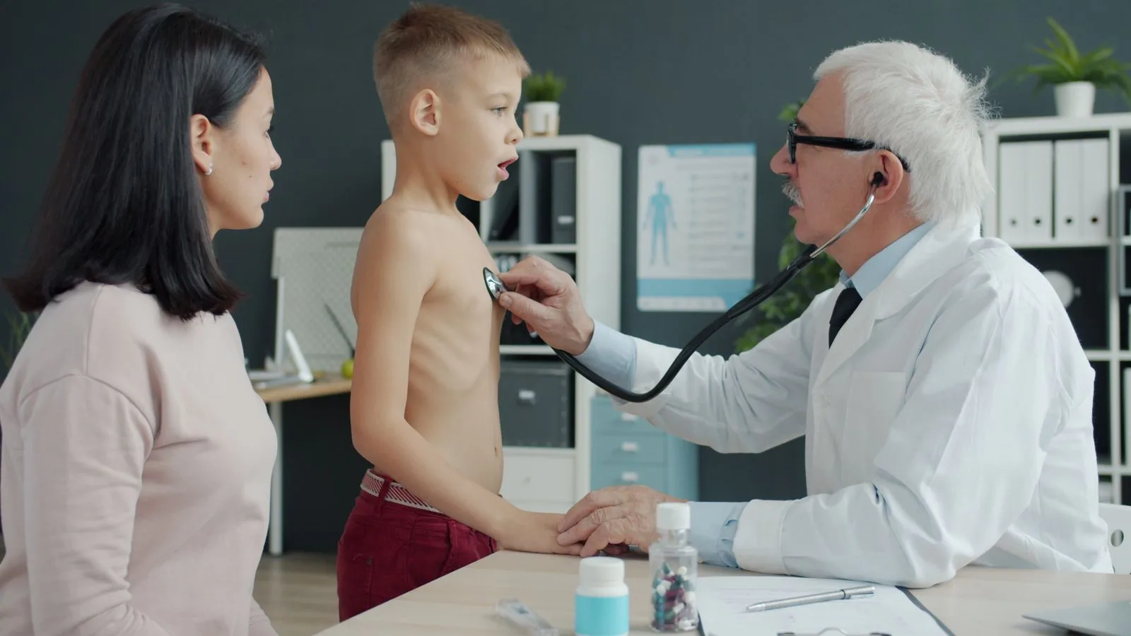 A doctor uses a stethoscope to examine a child in a clinical setting.