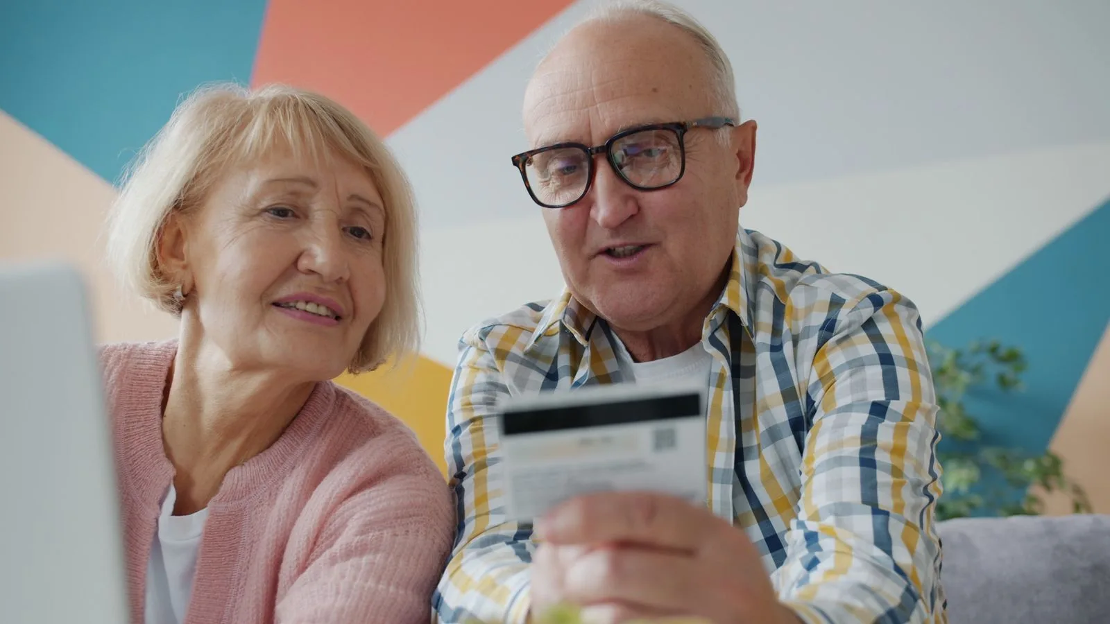 Senior couple using a credit card while shopping online at home.