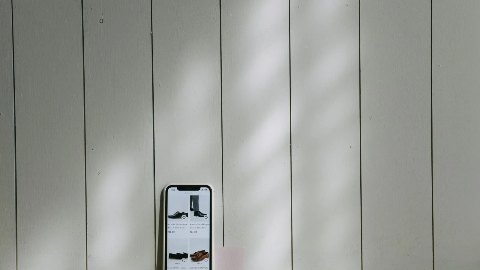 A smartphone and credit card sit on a wooden surface with soft lighting shadows.