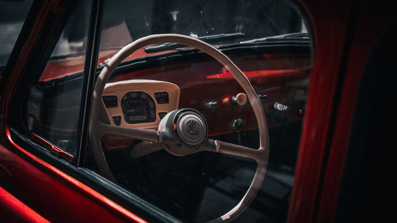 Close-up of a vintage car's steering wheel and dashboard, emphasizing a classic look.