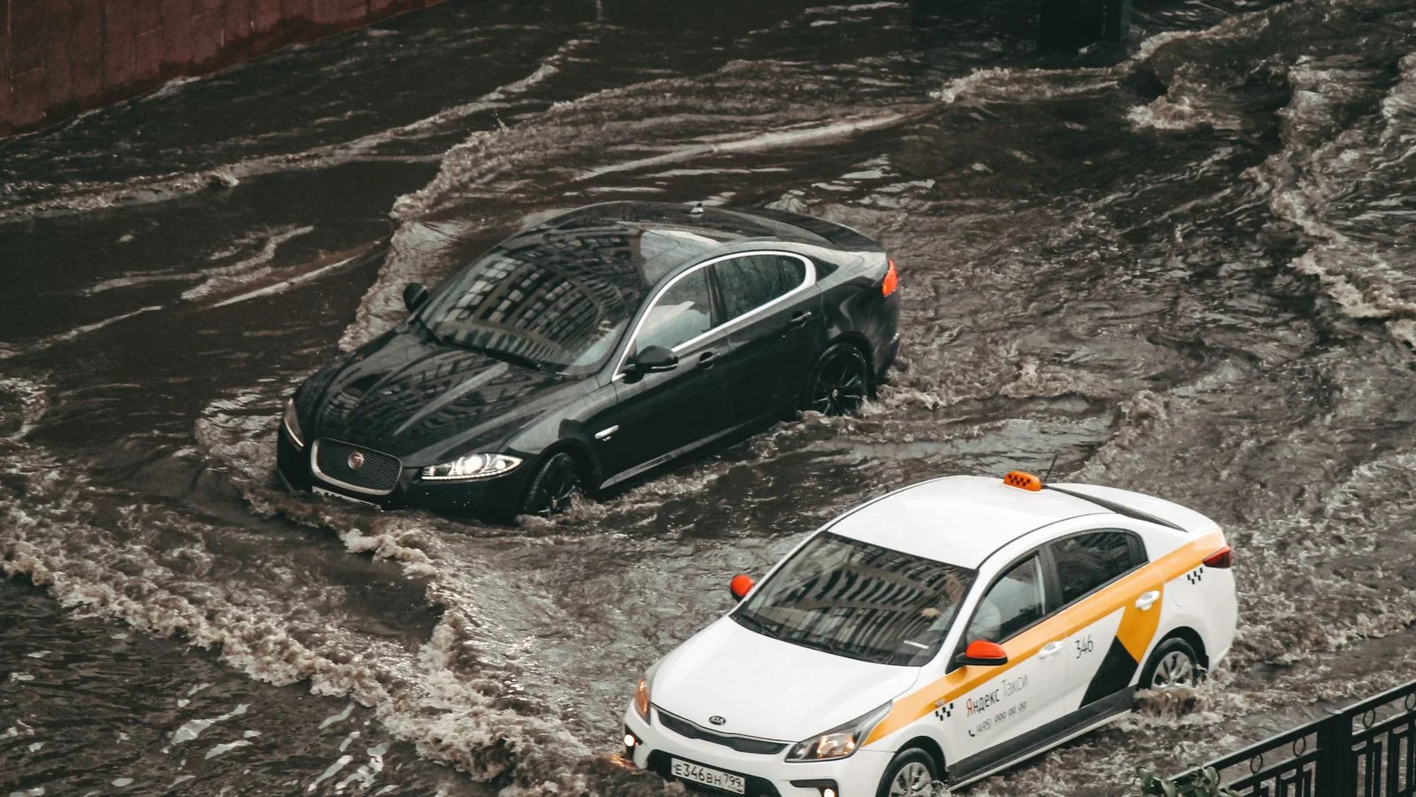 Cars navigating through a flooded city street, showcasing urban chaos and weather impacts.