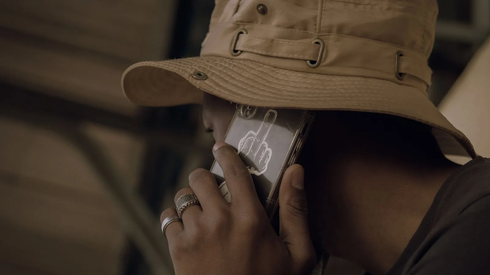 Close-up of a man wearing a hat talking on a cellphone with a unique case design.