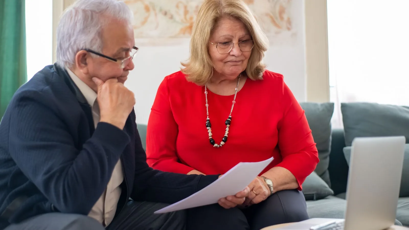 Elderly couple reviewing financial documents together at home in Portugal.