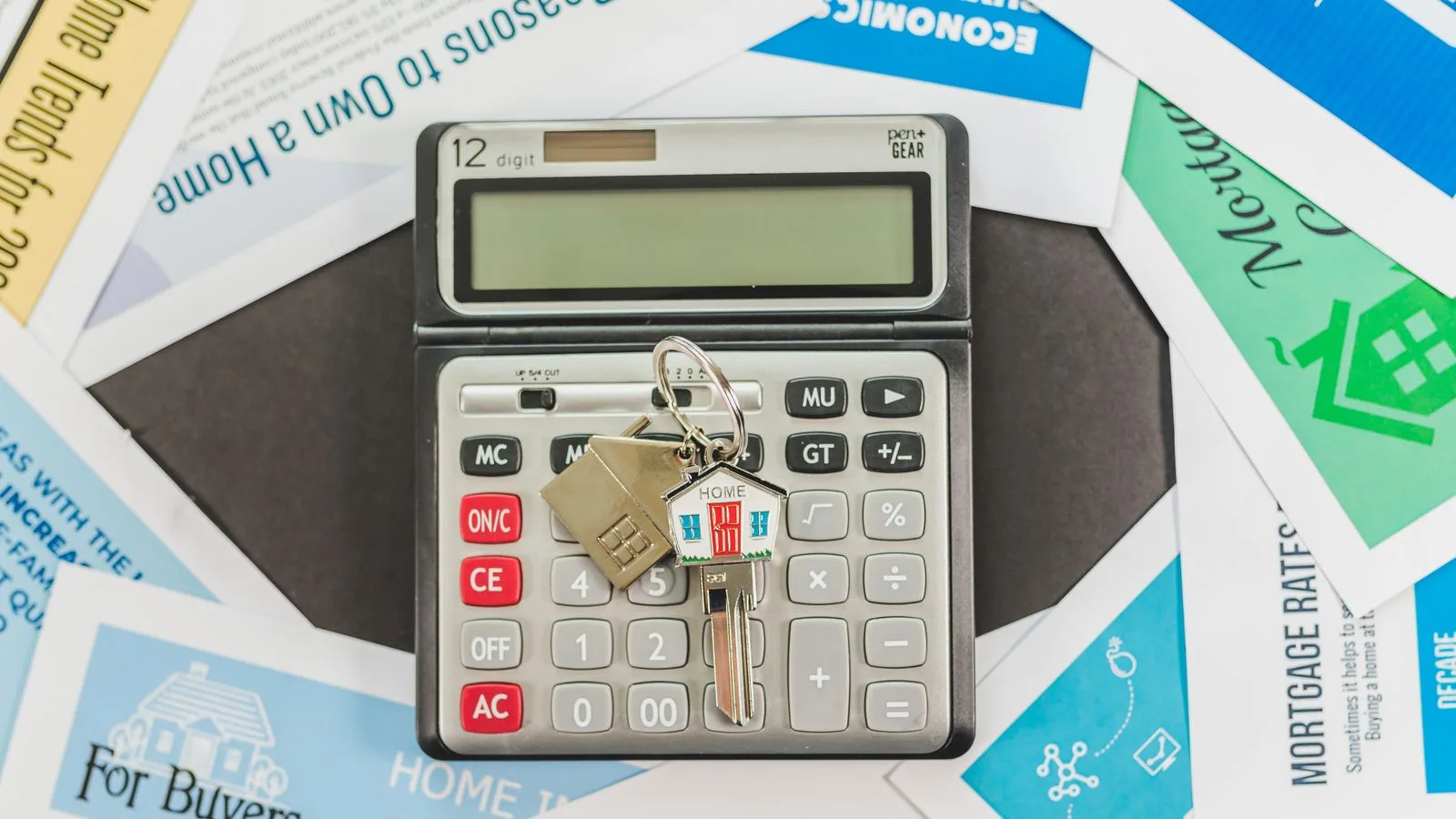 Calculator with keys and real estate documents symbolizes home buying finances.