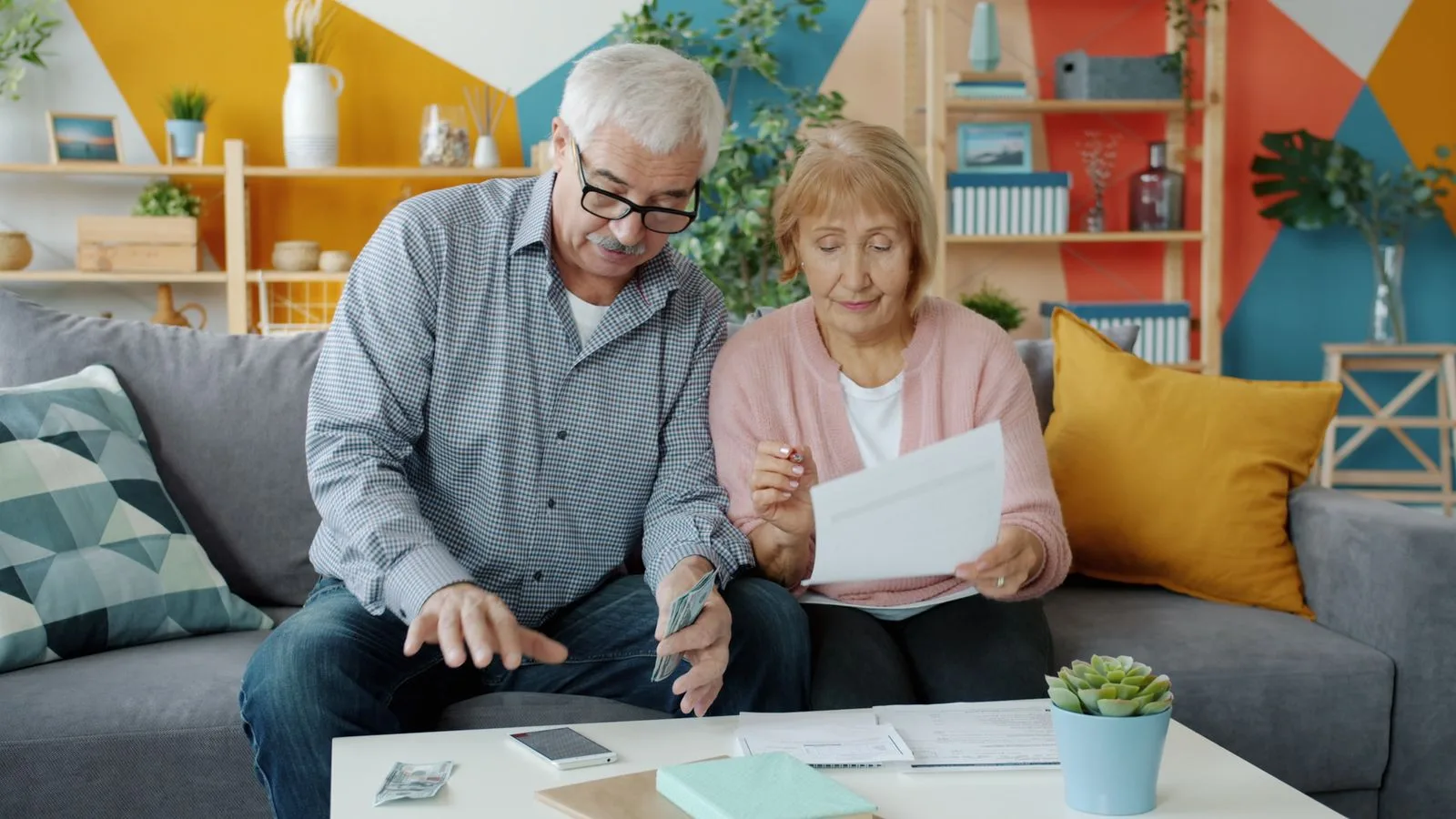 Elderly couple planning their budget, reviewing documents in a cozy living room.