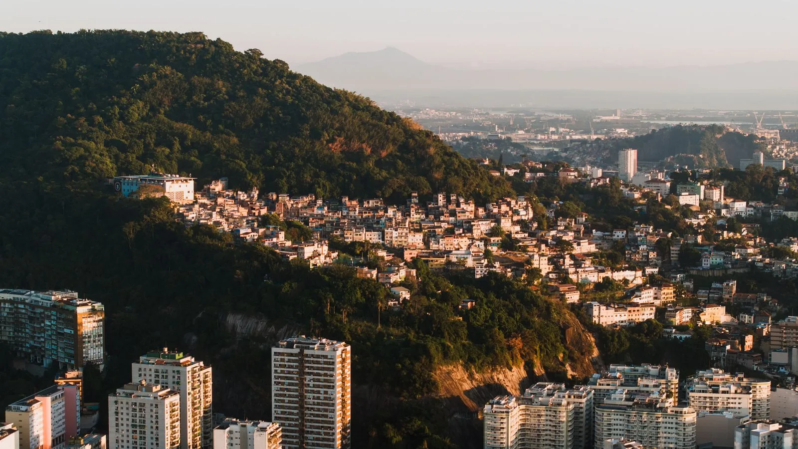 Stunning aerial view of Rio de Janeiro's cityscape with mountains and urban architecture at sunset.