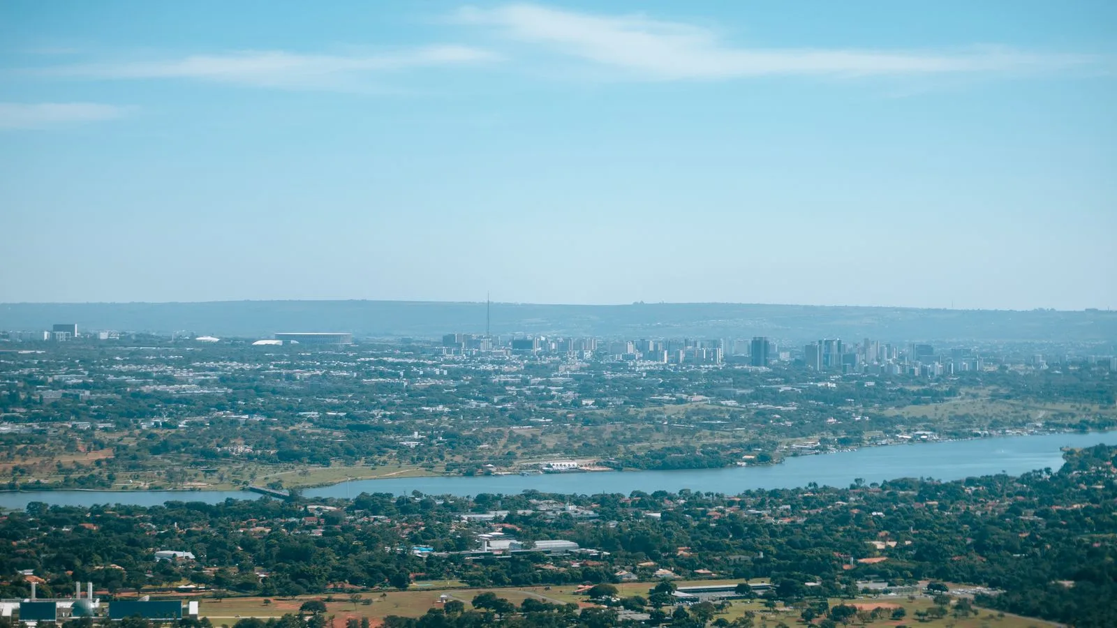 Aerial cityscape with skyline and river under clear blue sky.