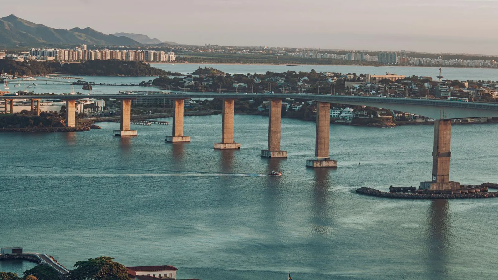 A breathtaking scenic view of a coastal city with a prominent bridge and calm waters at dusk.