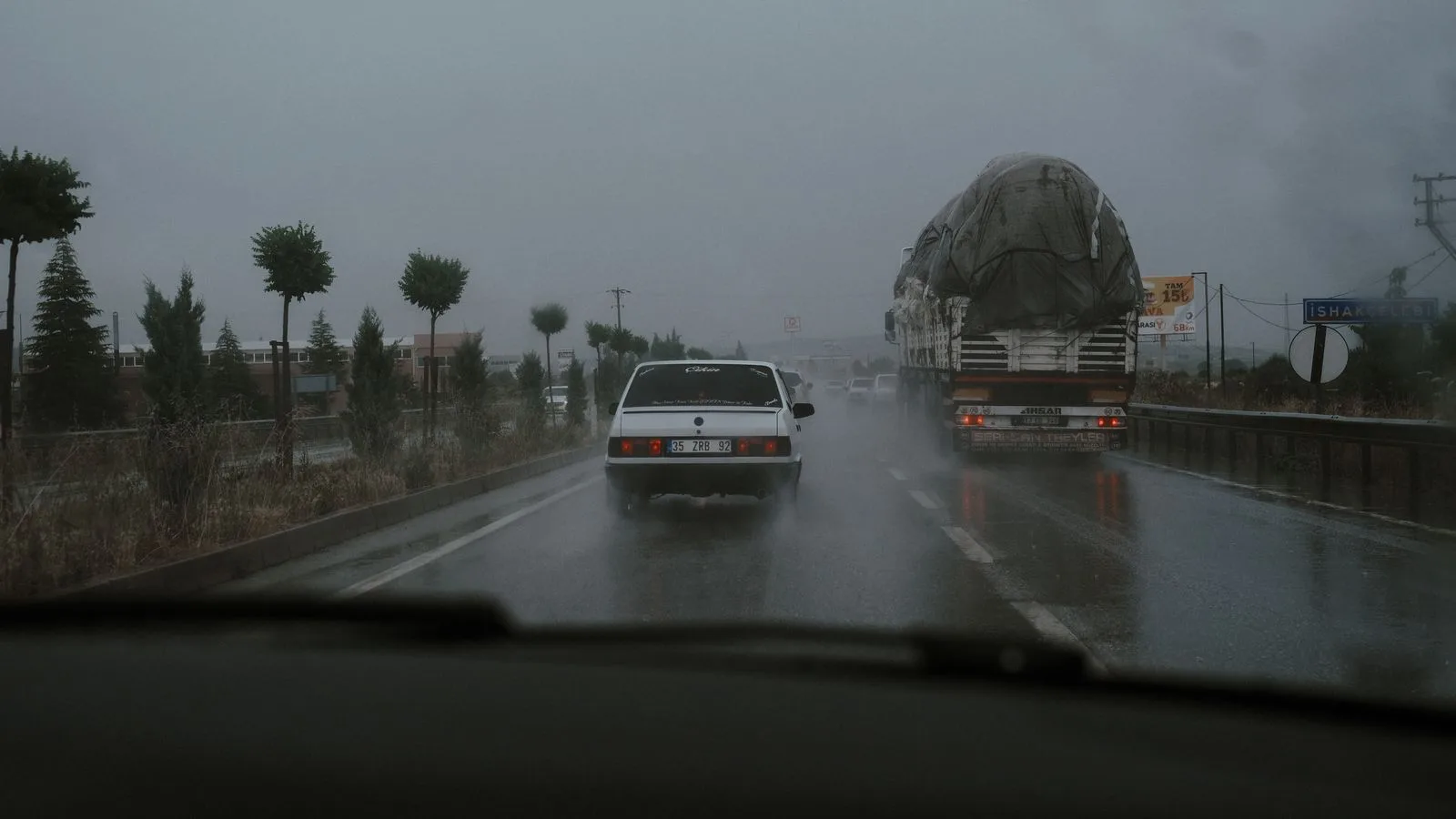 Vehicles driving on a wet highway during rainfall, showcasing road transportation challenges.
