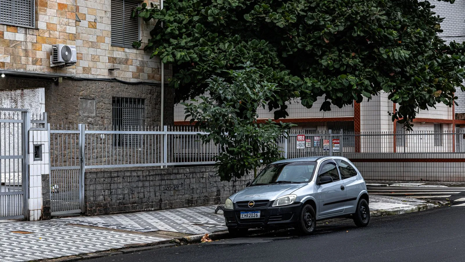 Quiet urban street in Praia Grande, São Paulo with a parked car and residential buildings.