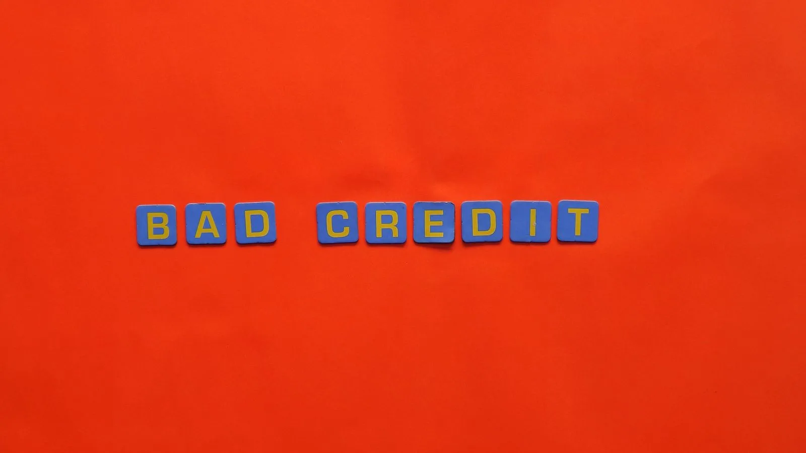 Blue letter blocks spelling 'Bad Credit' on an orange background.